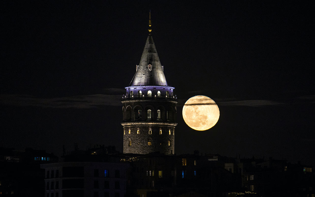 The Galata Tower lit at night by the full moon in Beyoğlu
