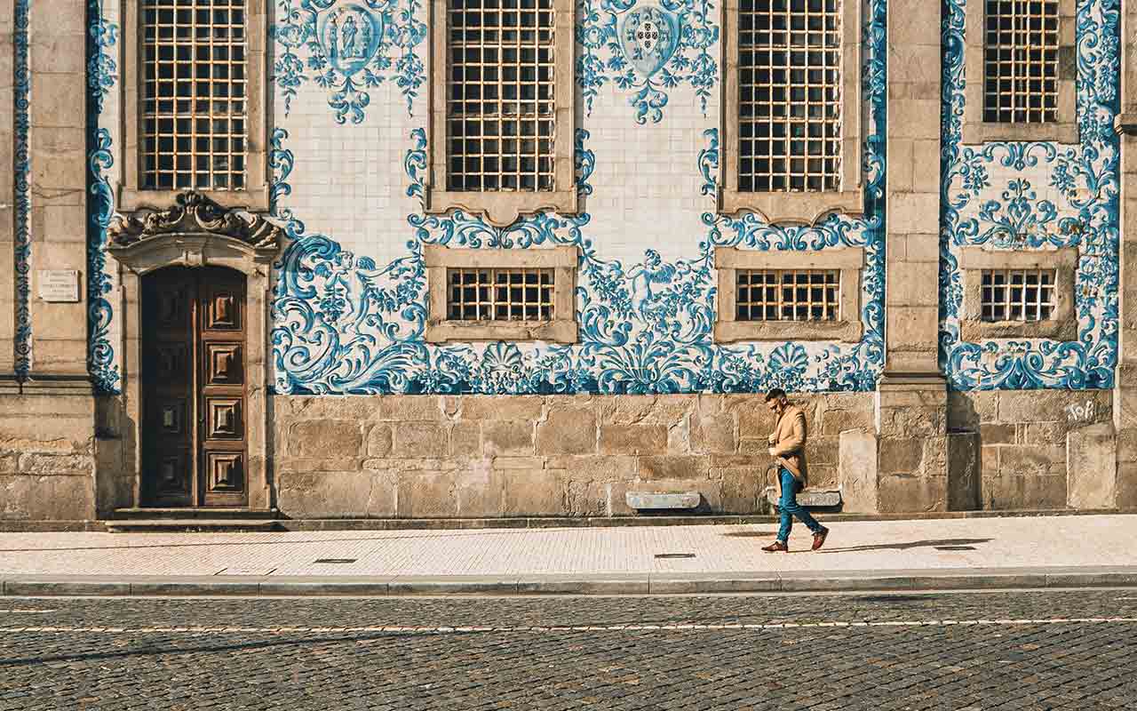 A tourist walking in the streets of Porto during on a bright and sunny day.