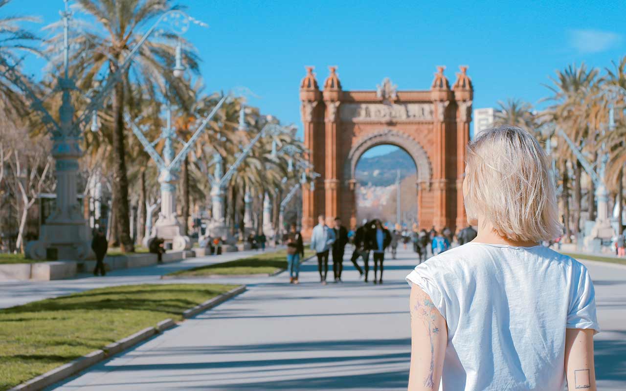 A tourist walking towards the  Arco de Triunfo de Barcelona. 
