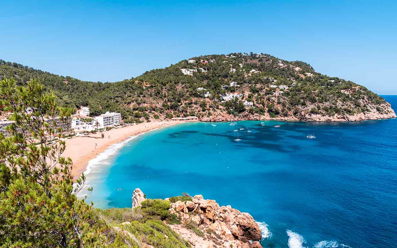 A view overlooking the turqouise colored beach landscape of a seaside resort in Ibiza